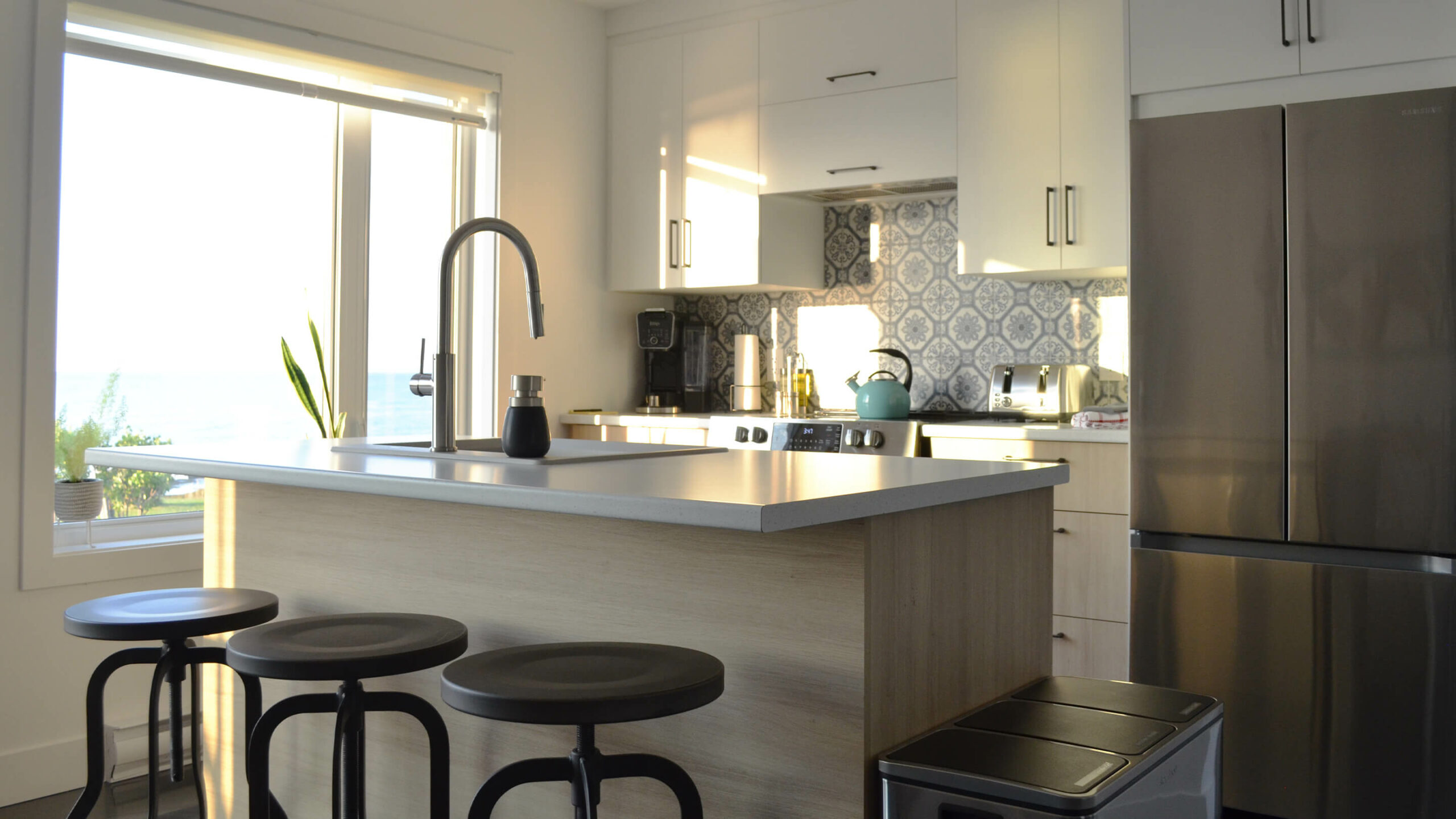 Cuisine toute équipée et moderne avec électroménagers en stainless et un îlot avec tabourets du chalet L’Écume des vagues au Logis du Bois Flotté