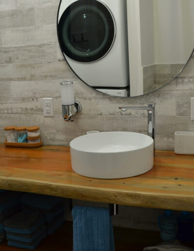 Lavabo avec miroir rond et plan de travail en bois de la salle de bain du chalet Le Clapotis de la marée au Logis du Bois Flotté