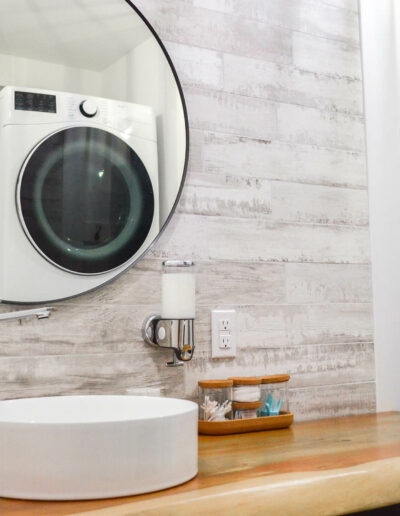 Lavabo avec miroir rond et plan de travail en bois de la salle de bain du chalet Le Fleuve tranquille au Logis du Bois Flotté