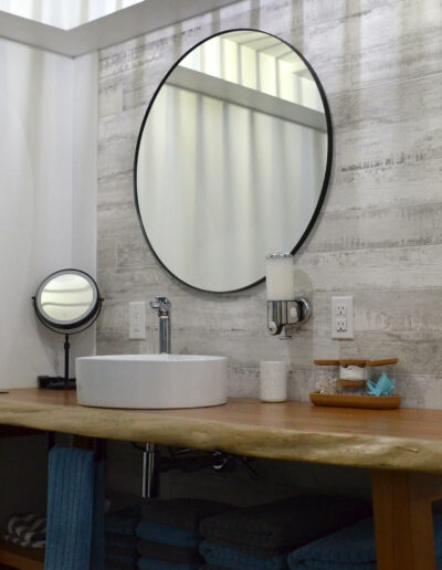 Lavabo avec miroir rond et plan de travail en bois de la salle de bain du chalet L’Écume des vagues au Logis du Bois Flotté