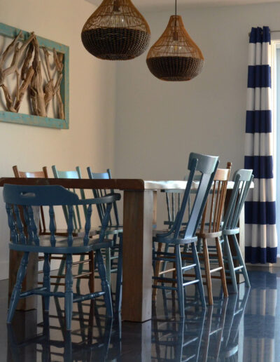 Salle à manger pour 8 personnes avec table en bois et chaises en bois colorées avec une décoration personnalisée du chalet L’Écume des vagues au Logis du Bois Flotté