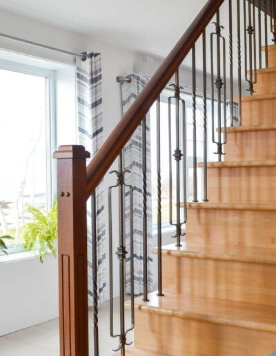 Escalier en bois et vaste fenestration donnant sur le fleuve du chalet Les Grandes Marées au Logis du Bois Flotté